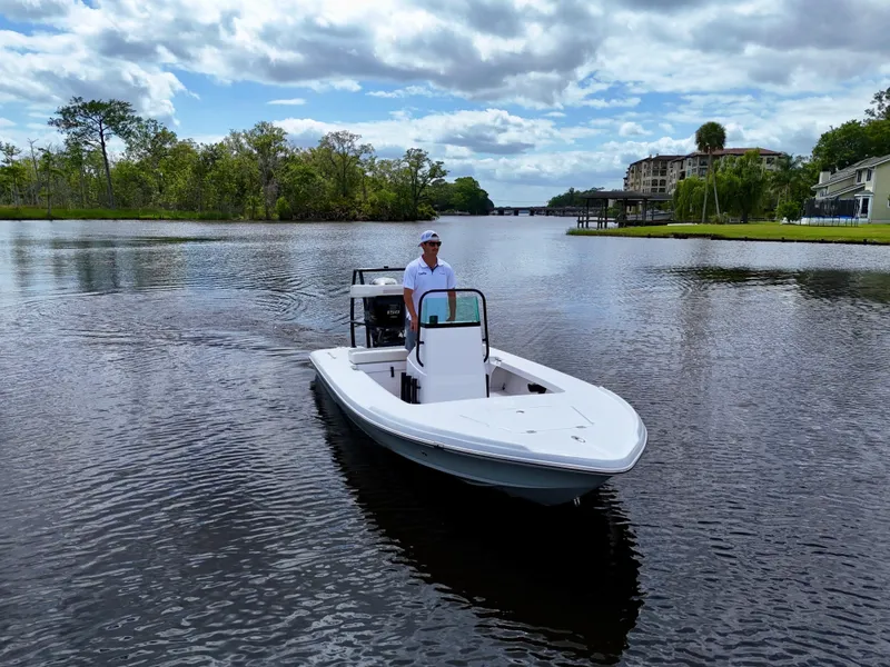 Slide: The Image of 2025 Action Craft 17 Flats boat on a calm river with scenic background. - 13