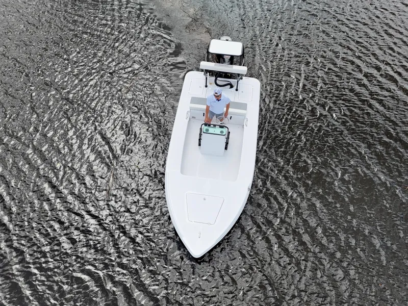Slide: The Image of 2025 Action Craft 17 Flats boat on water, aerial view, with person steering. - 17