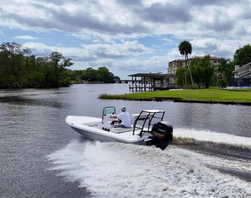Slide: The Image of 2025 Action Craft 17 Flats boat cruising on a scenic river under a cloudy sky. - 20