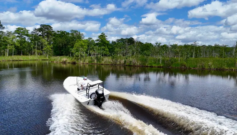 Slide: The Image of 2025 Action Craft 17 Flats boat cruising on a scenic river under a blue sky. - 23