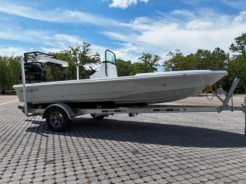 Slide: The Image of 2025 Action Craft 17 Flats boat on trailer, parked outdoors under a clear sky. - 31