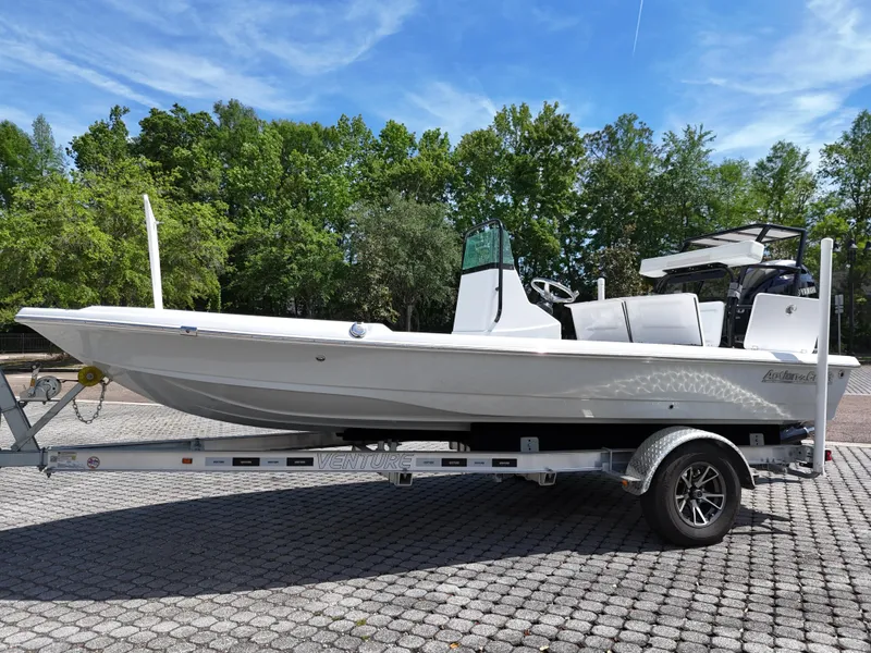 Slide: The Image of 2025 Action Craft 17 Flats boat on trailer, parked outdoors with trees in background. - 35