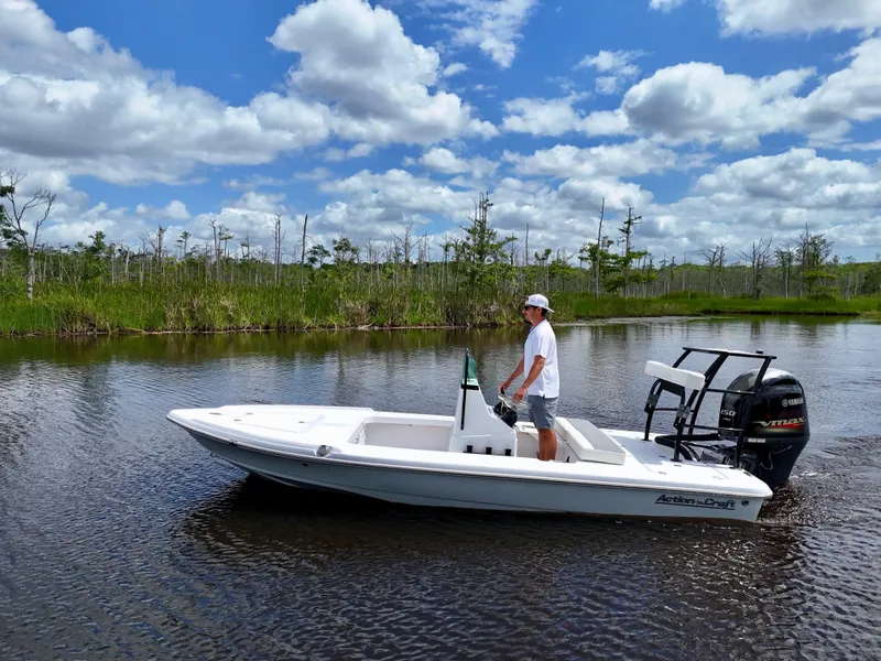 Slide: The Image of 2025 Action Craft 17 Flats boat on calm water, under a blue sky with clouds. - 8