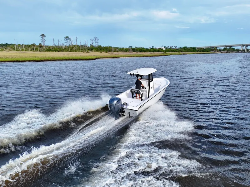 Slide: The Image of 2025 Action Craft 24 Coastal Bay boat cruising on a scenic river. - 25