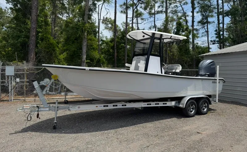 Slide: The Image of 2025 Action Craft 24 Coastal Bay boat on trailer, parked outdoors near trees. - 34