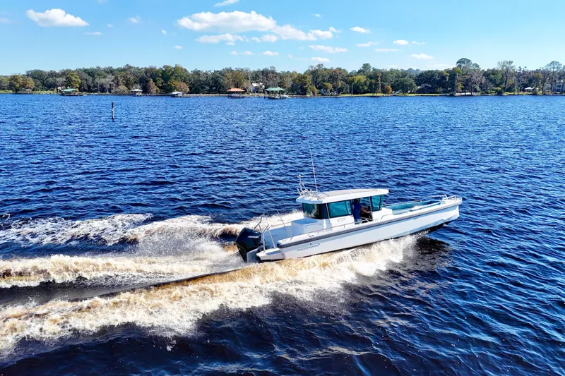 Slide: The Image of 2020 Axopar 28 CABIN cruising on a scenic lake under a clear blue sky. - 11