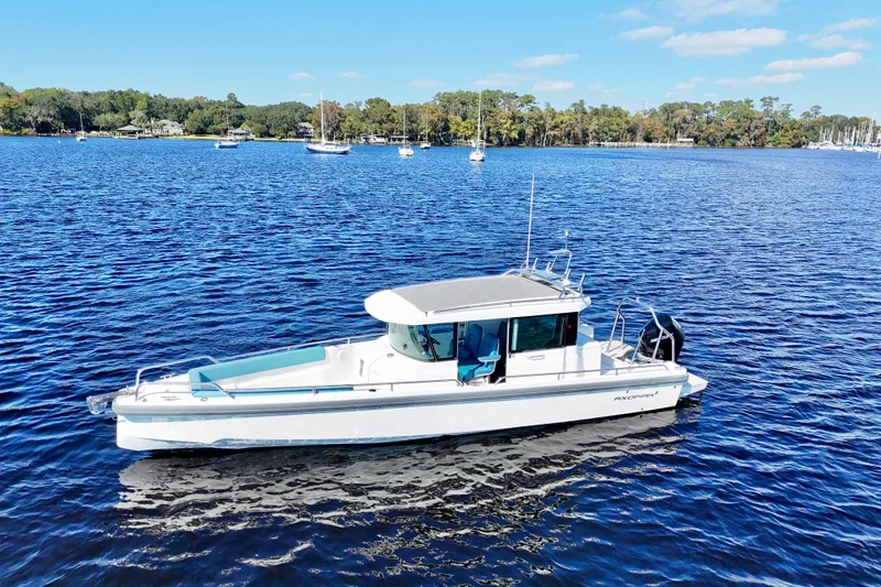 Slide: The Image of 2020 Axopar 28 CABIN boat on a serene lake with clear blue skies. - 12
