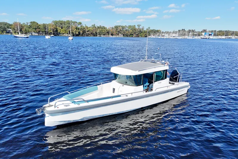 Slide: The Image of 2020 Axopar 28 CABIN boat on a calm blue lake with trees in the background. - 13