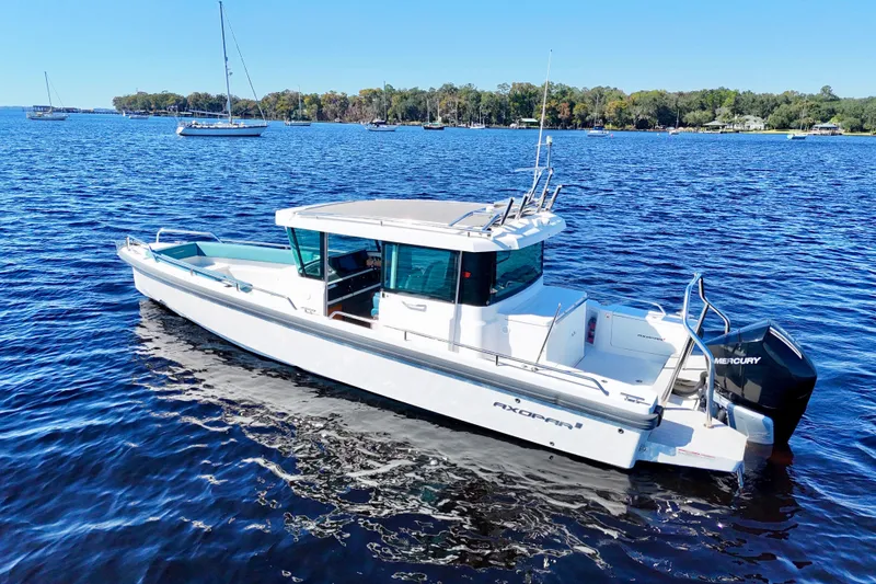 Slide: The Image of 2020 Axopar 28 CABIN boat on a calm lake with clear blue skies. - 21