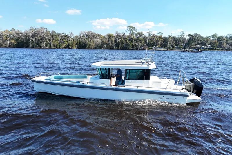 Slide: The Image of 2020 Axopar 28 CABIN boat cruising on a scenic lake under a clear blue sky. - 22