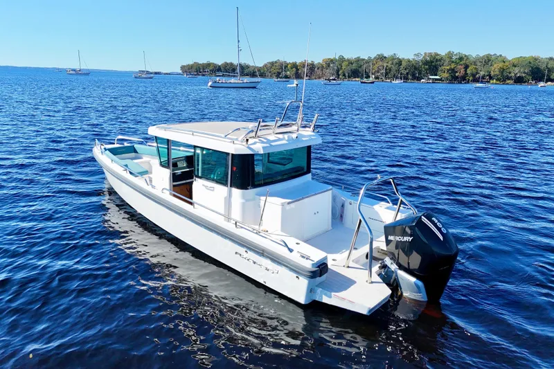 Slide: The Image of 2020 Axopar 28 CABIN boat on calm blue water with trees in the background. - 23