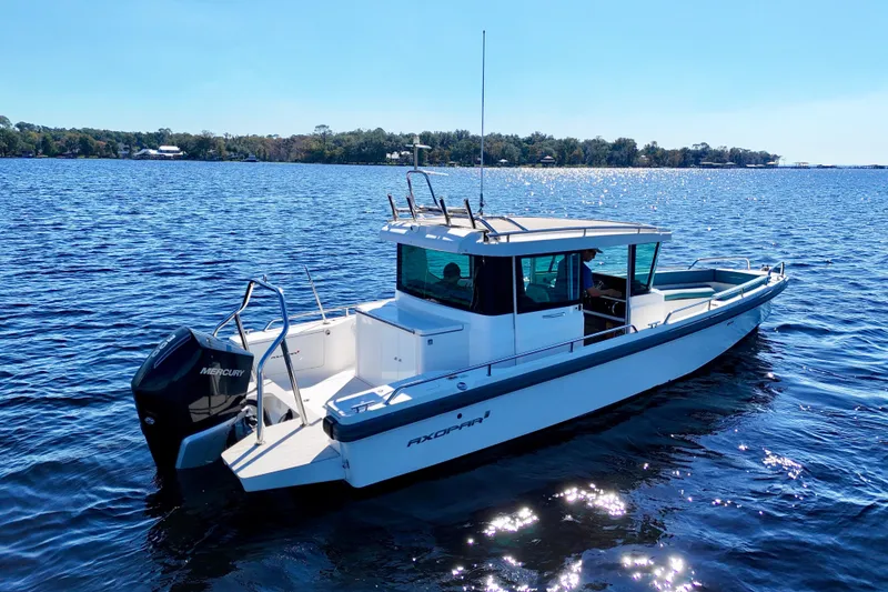 Slide: The Image of 2020 Axopar 28 CABIN boat on a sunny lake, featuring a Mercury engine. - 29