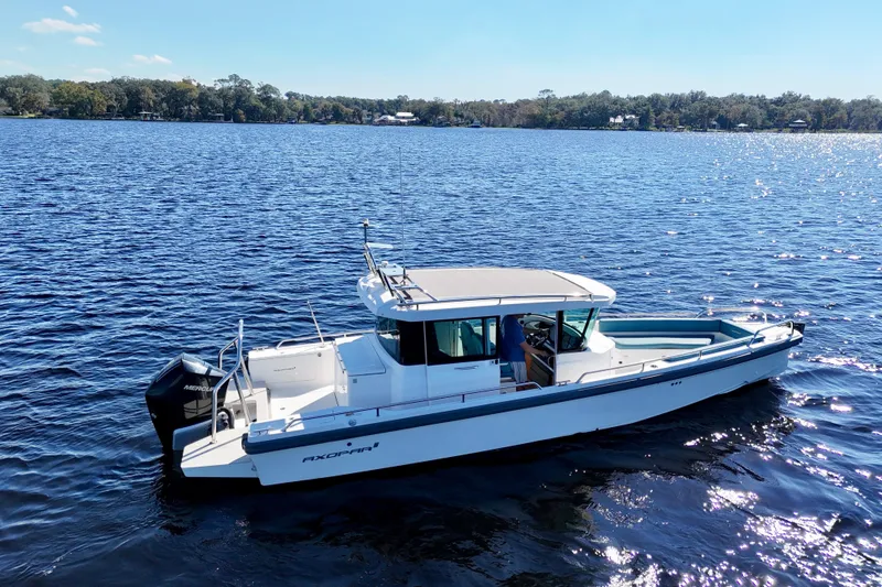 Slide: The Image of 2020 Axopar 28 CABIN boat cruising on a sunny lake. - 30