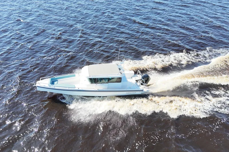 Slide: The Image of 2020 Axopar 28 CABIN cruising on open water, creating a dynamic wake. - 34