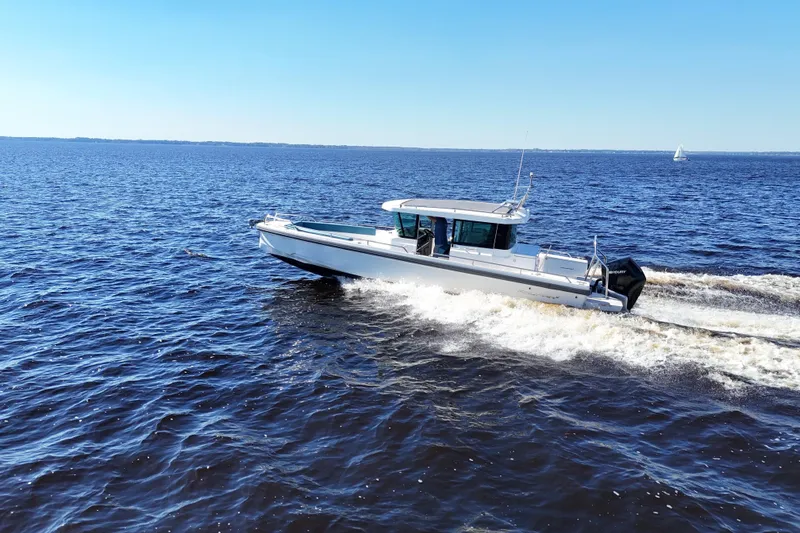 Slide: The Image of 2020 Axopar 28 CABIN cruising on open water under clear blue skies. - 39