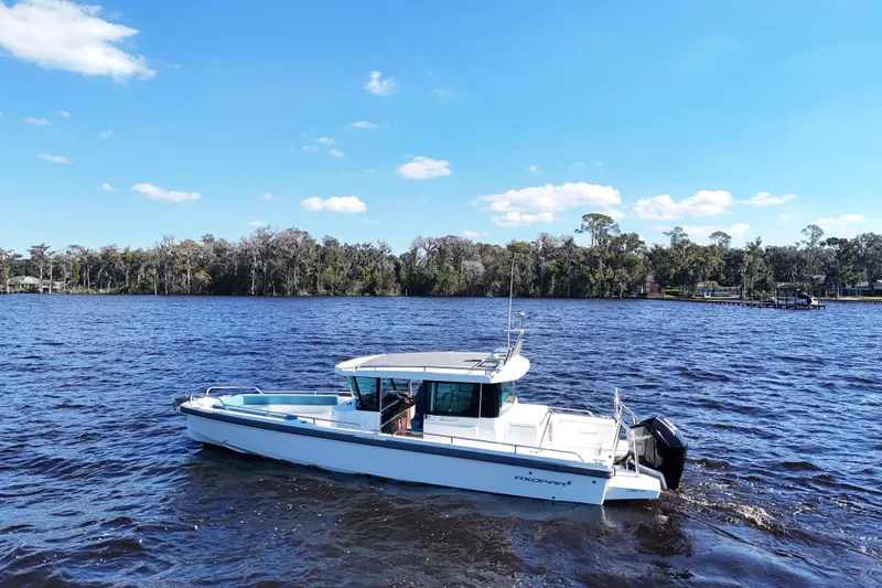 Slide: The Image of 2020 Axopar 28 CABIN boat on a serene lake with a forested shoreline. - 40