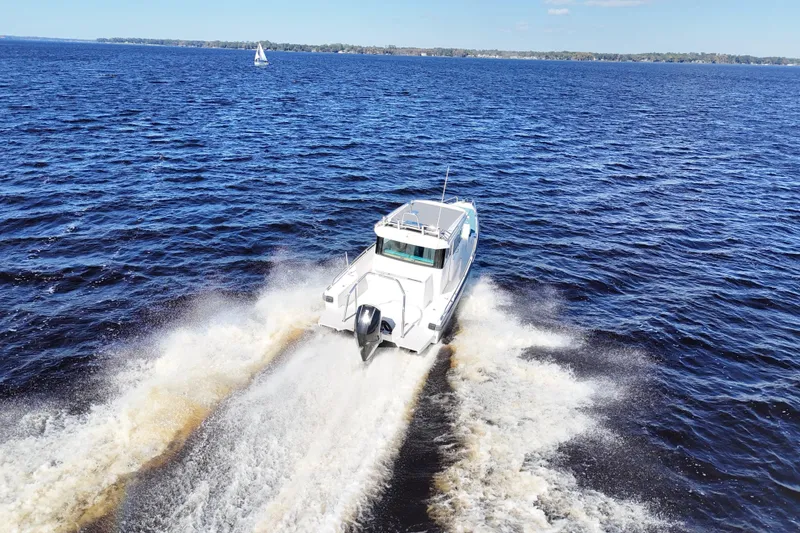 Slide: The Image of 2020 Axopar 28 CABIN boat cruising on open water, creating a wake. - 43