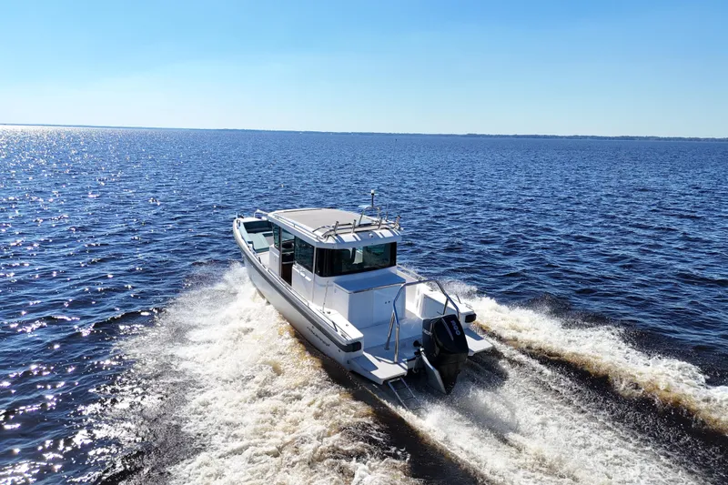 Slide: The Image of 2020 Axopar 28 CABIN cruising on open water under clear blue skies. - 7