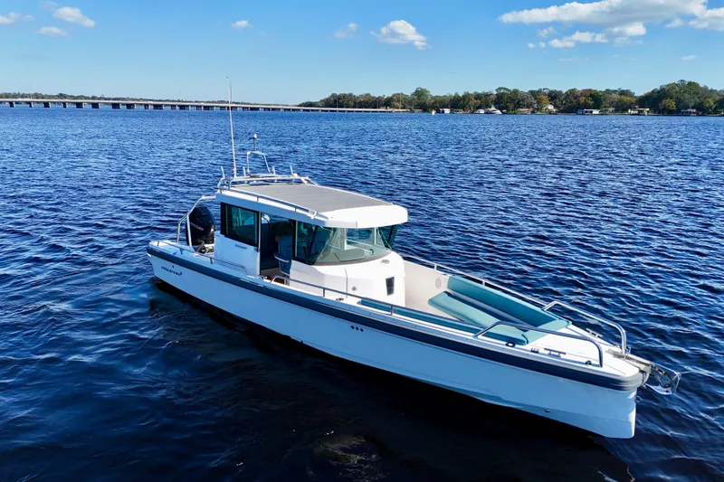 Slide: The Image of 2020 Axopar 28 CABIN boat on a serene blue lake under a clear sky. - 15