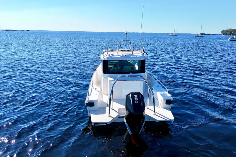 Slide: The Image of 2020 Axopar 28 CABIN boat on calm blue water, rear view. - 25