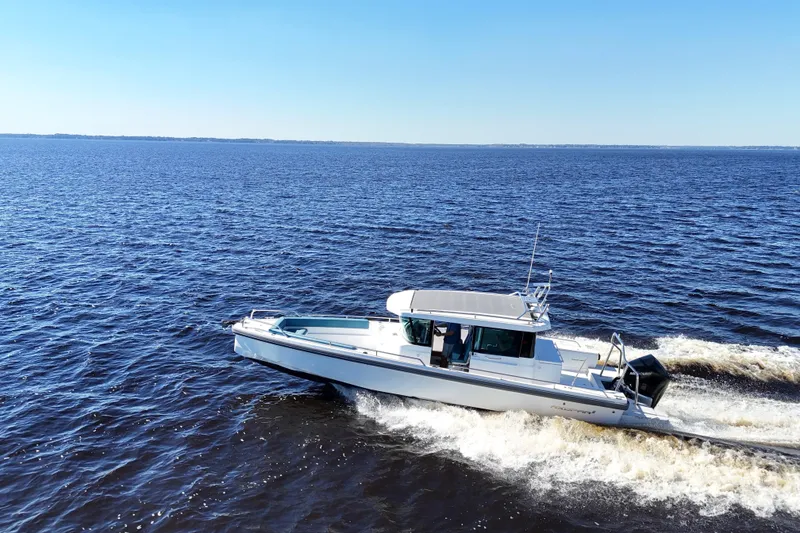 Slide: The Image of 2020 Axopar 28 CABIN boat cruising on open water under clear blue sky. - 3