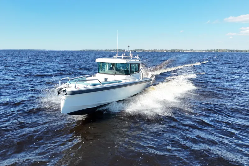 Slide: The Image of 2020 Axopar 28 CABIN A/C cruising on open water under clear blue skies. - 4