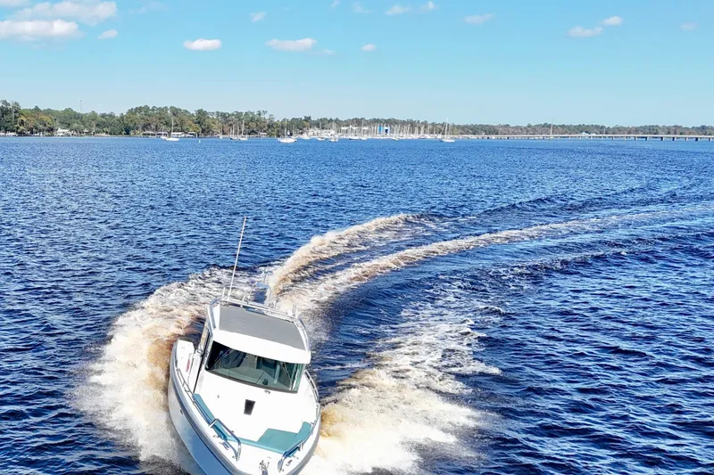 Slide: The Image of 2020 Axopar 28 CABIN boat cruising on a sunny lake with clear skies. - 5