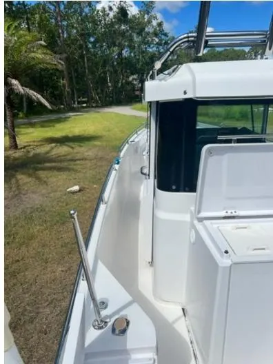 Slide: The Image of 2020 Axopar 28 boat, side view, white exterior, surrounded by greenery and trees. - 56