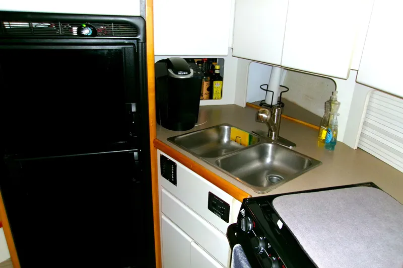 Slide: The Image of Compact kitchen area in a 1995 Carver 355 Aft Cabin Motor Yacht with sink and appliances. - 14