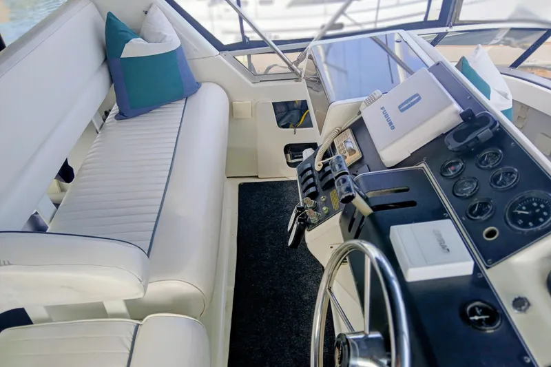 Slide: The Image of 1995 Carver 355 Aft Cabin Motor Yacht helm with white seating and navigation controls. - 26