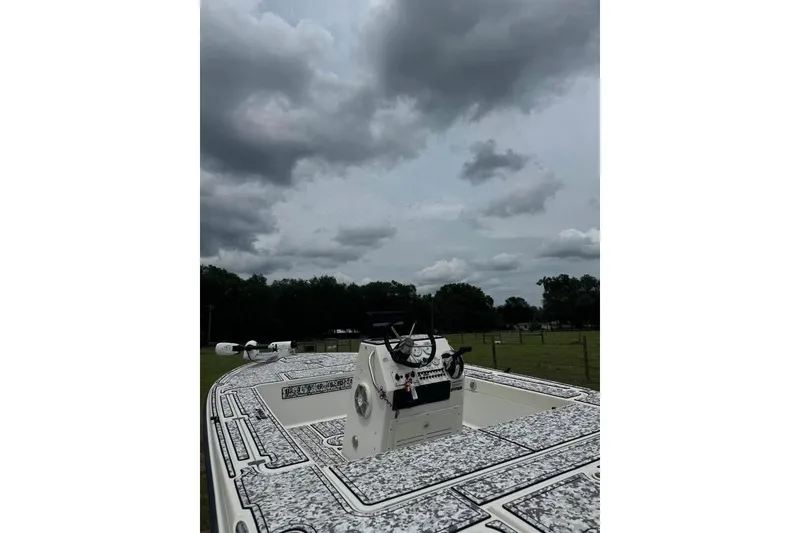 Slide: The Image of 2006 Triton 191 LTS boat under cloudy sky, parked in a grassy area. - 2