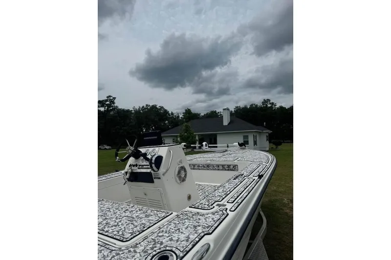 Slide: The Image of 2006 Triton 191 LTS boat with patterned deck, under cloudy sky near a house. - 3