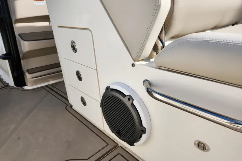 Slide: The Image of 2022 Boston Whaler 330 Outrage interior with speaker, storage drawers, and cushioned seating. - 16