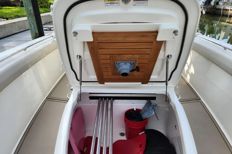 Slide: The Image of 2022 Boston Whaler 330 Outrage storage compartment with open hatch, showcasing interior space. - 27
