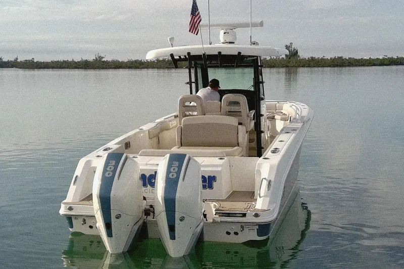 Slide: The Image of 2022 Boston Whaler 330 Outrage boat on calm water, rear view with dual engines. - 4