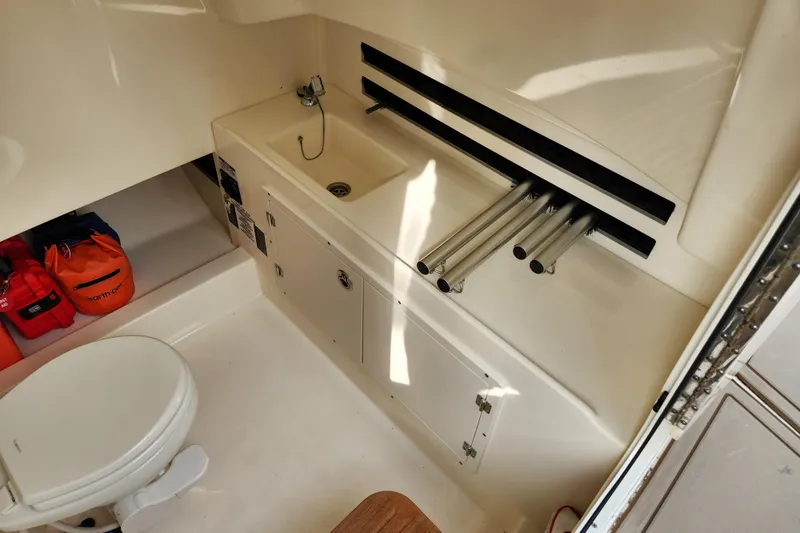 Slide: The Image of 2022 Boston Whaler 330 Outrage interior with sink, toilet, and storage compartments. - 51