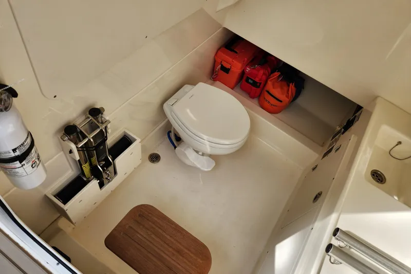 Slide: The Image of 2022 Boston Whaler 330 Outrage cabin interior with toilet and safety equipment. - 52