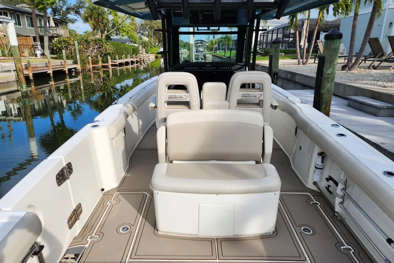 Slide: The Image of 2022 Boston Whaler 330 Outrage boat interior with seating and console, docked by a canal. - 7