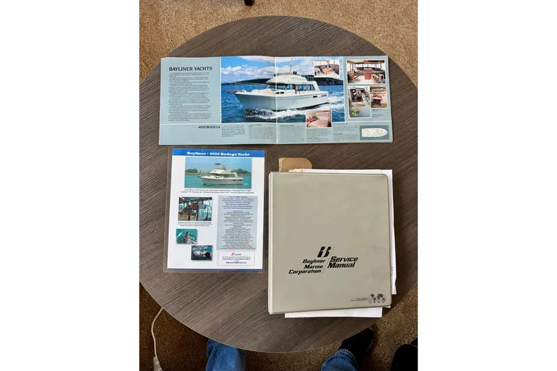 Slide: The Image of 1982 Bayliner 4050 Bodega yacht brochures and service manual on a round table. - 18