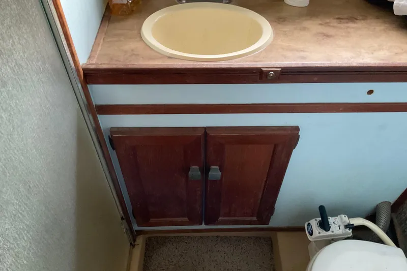 Slide: The Image of 1982 Bayliner 4050 Bodega bathroom with sink, wooden cabinet, and marine toilet. - 22