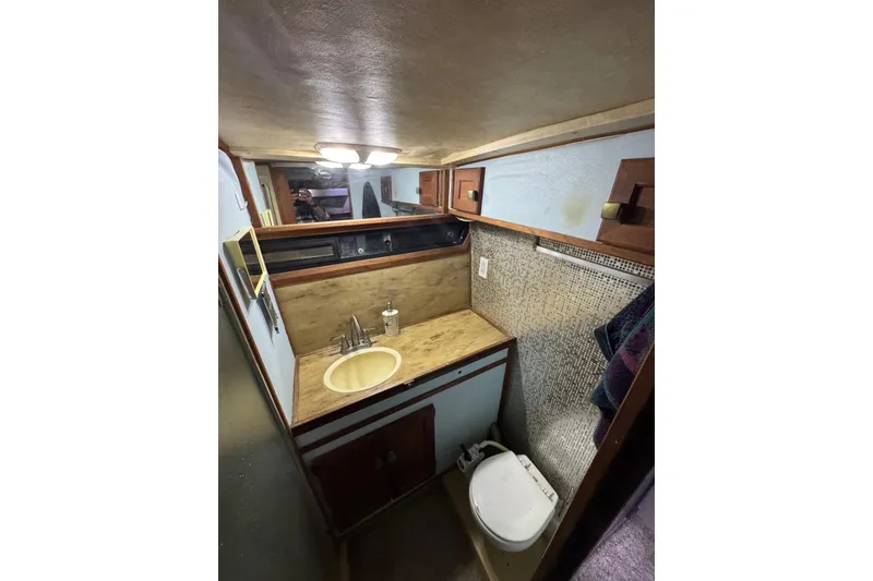 Slide: The Image of 1982 Bayliner 4050 Bodega bathroom with sink, toilet, and wooden cabinetry. - 24