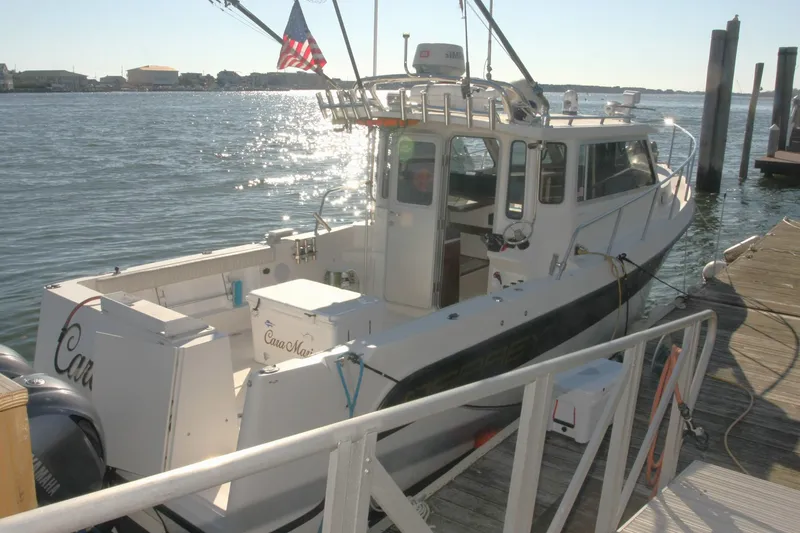 Slide: The Image of 2017 Osprey 30 Fisherman boat deck with fishing rod holders, docked by the water. - 22