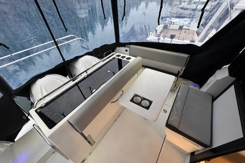 Slide: The Image of 2025 Jeanneau NC 895 Sport Series 2 interior with seating and table, overlooking marina. - 36