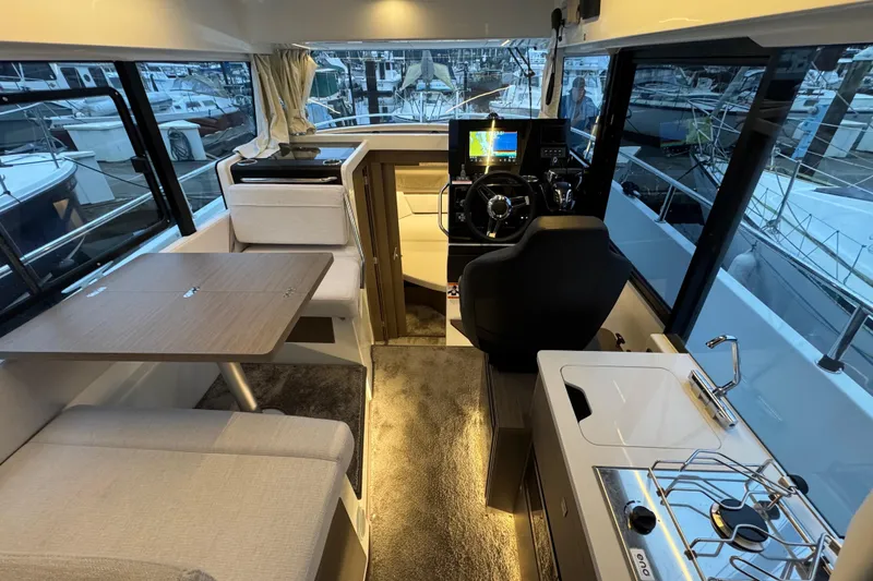 Slide: The Image of 2025 Jeanneau NC 895 Sport Series 2 interior with helm, dining area, and kitchenette. - 4