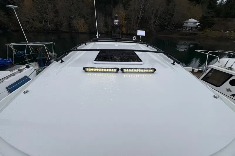 Slide: The Image of 2025 Jeanneau NC 895 Sport Series 2 boat deck with LED lights, docked by a forested shoreline. - 63