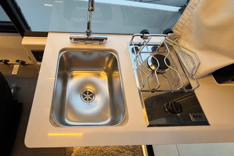Slide: The Image of Compact kitchen area in 2025 Jeanneau NC 895 Sport Series 2 with sink and stove. - 9