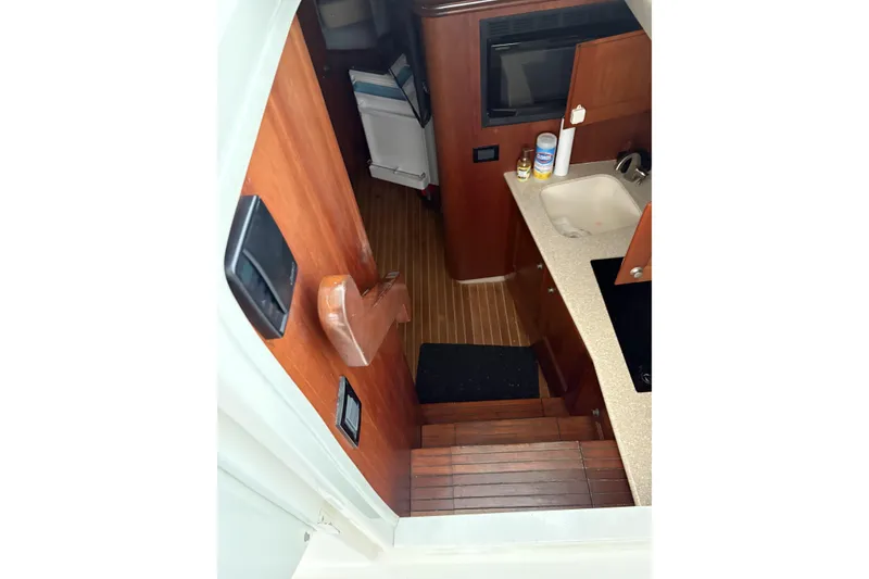 Slide: The Image of Interior view of 2006 Rampage 38 Express boat, featuring wooden stairs and compact kitchen area. - 20