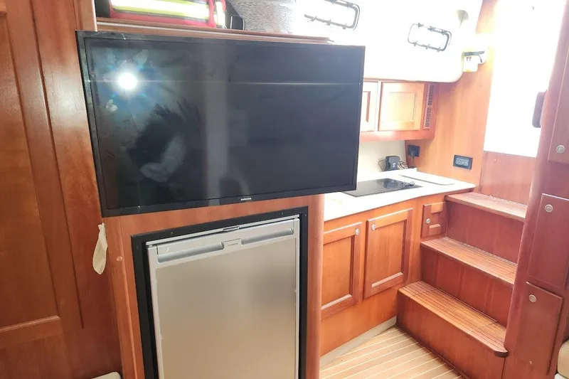 Slide: The Image of Interior of 2006 Rampage 38 Express yacht with TV, fridge, and kitchenette. - 22