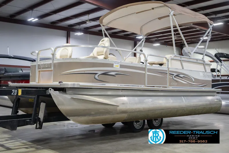 Slide: The Image of 2009 Sylvan 818 Mirage Fish pontoon boat in indoor showroom, beige with canopy. - 4