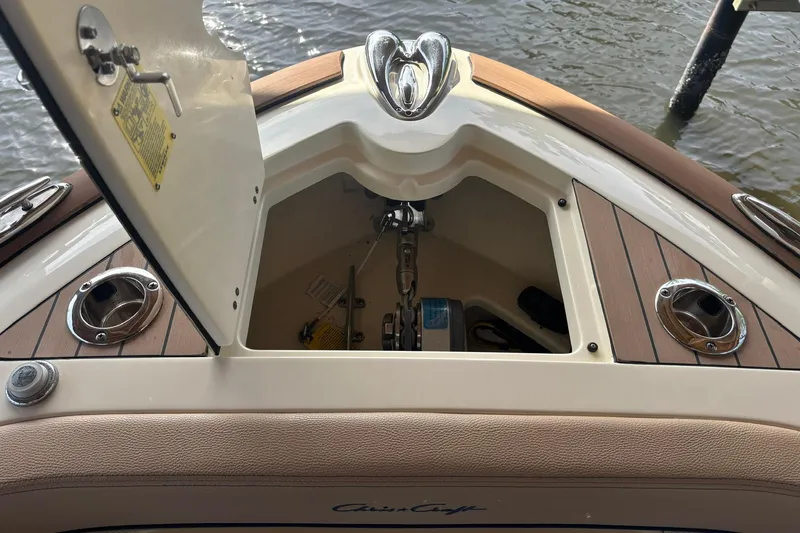 Slide: The Image of 2023 Chris-Craft Calypso 24 anchor compartment with open hatch, showcasing teak deck details. - 17